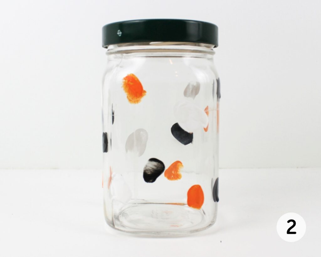 Glass jar covered with black, white and orange fingerprints.
