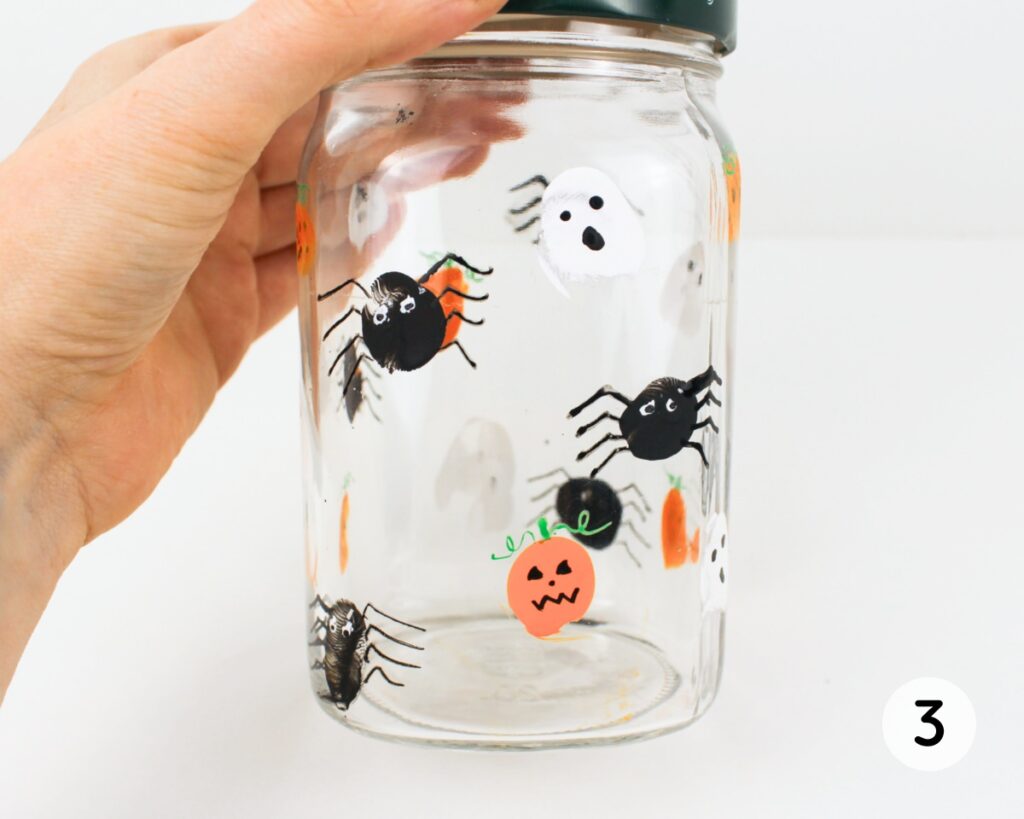 Glass jar covered with little ghosts, spiders and jack-o'-lanterns.