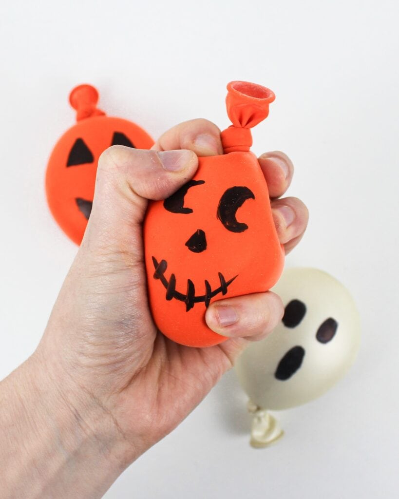 Hand squishing a jack-o'-lantern stress ball.