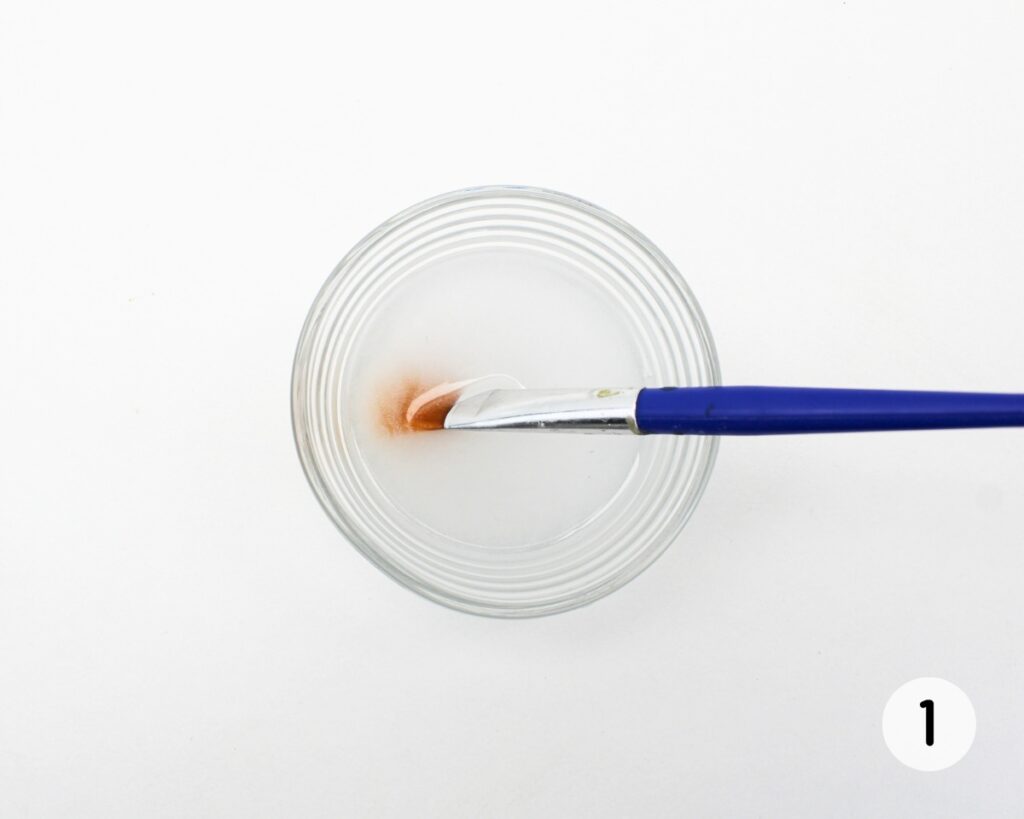 Small glass bowl with salt water and paintbrush.