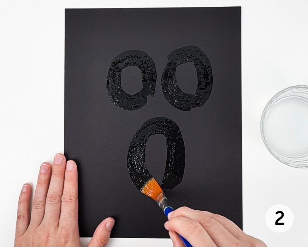 Black cardstock with 3 circles painted with salt water.
