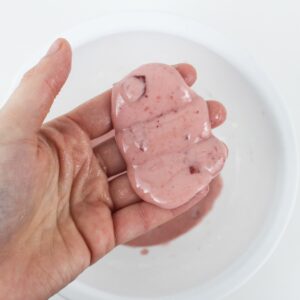Hand holding oozing pink slime.