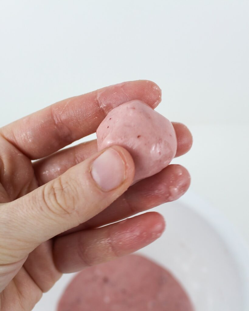 Hand holding a ball of pink slime.