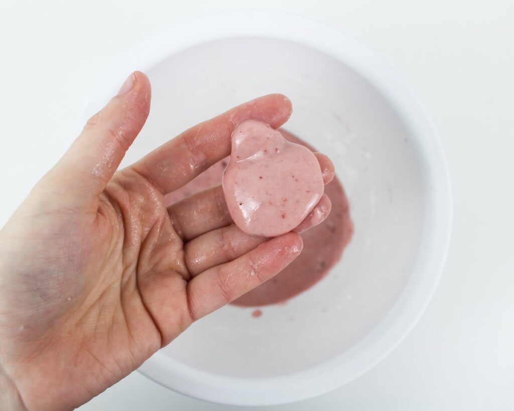Hand holding oozing pink slime.
