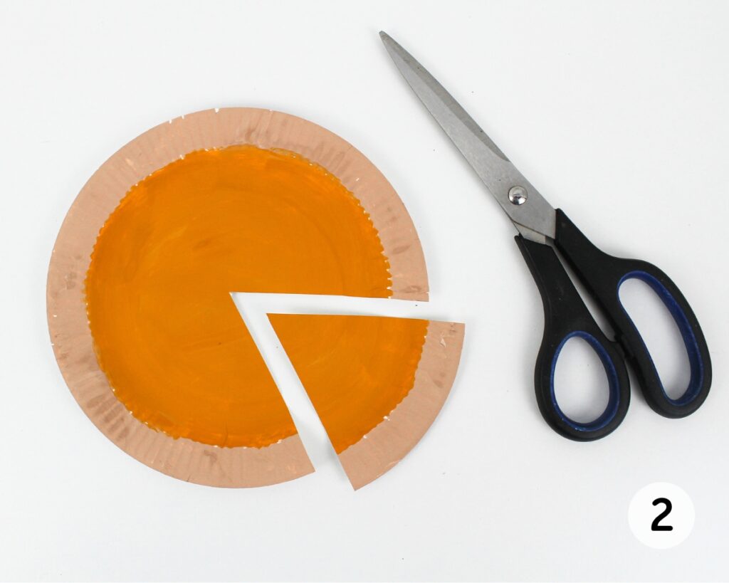 Painted paper plate with a triangle cut out with scissors.