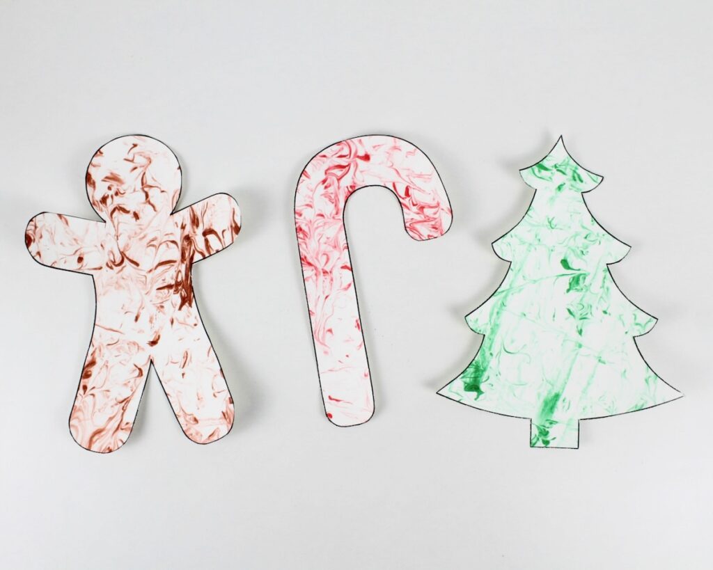 Gingerbread man, candy cane and Christmas tree crafts with marbled patterns.