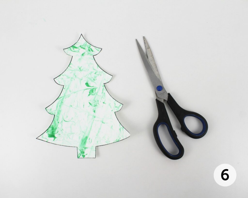 Christmas tree cut out of printed template with scissors.