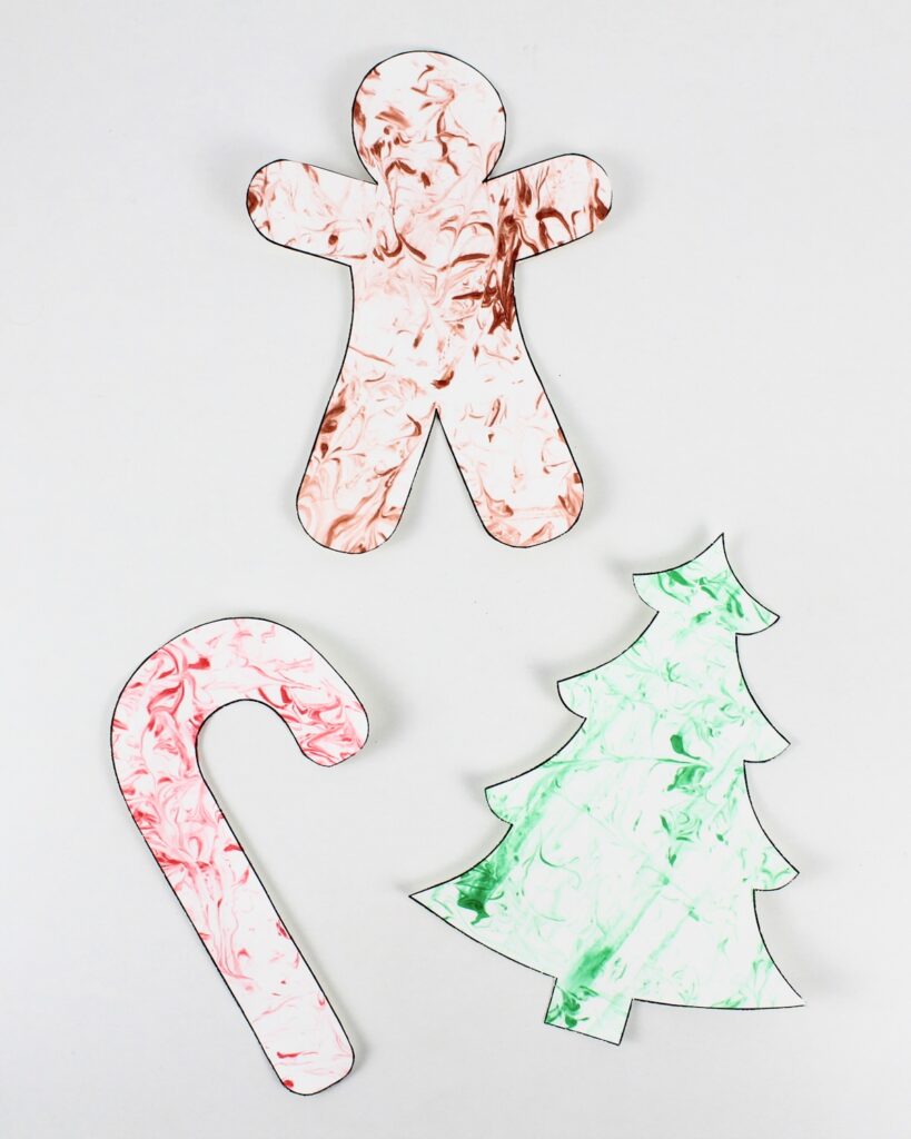 Gingerbread man, candy cane and Christmas tree crafts with marbled patterns.