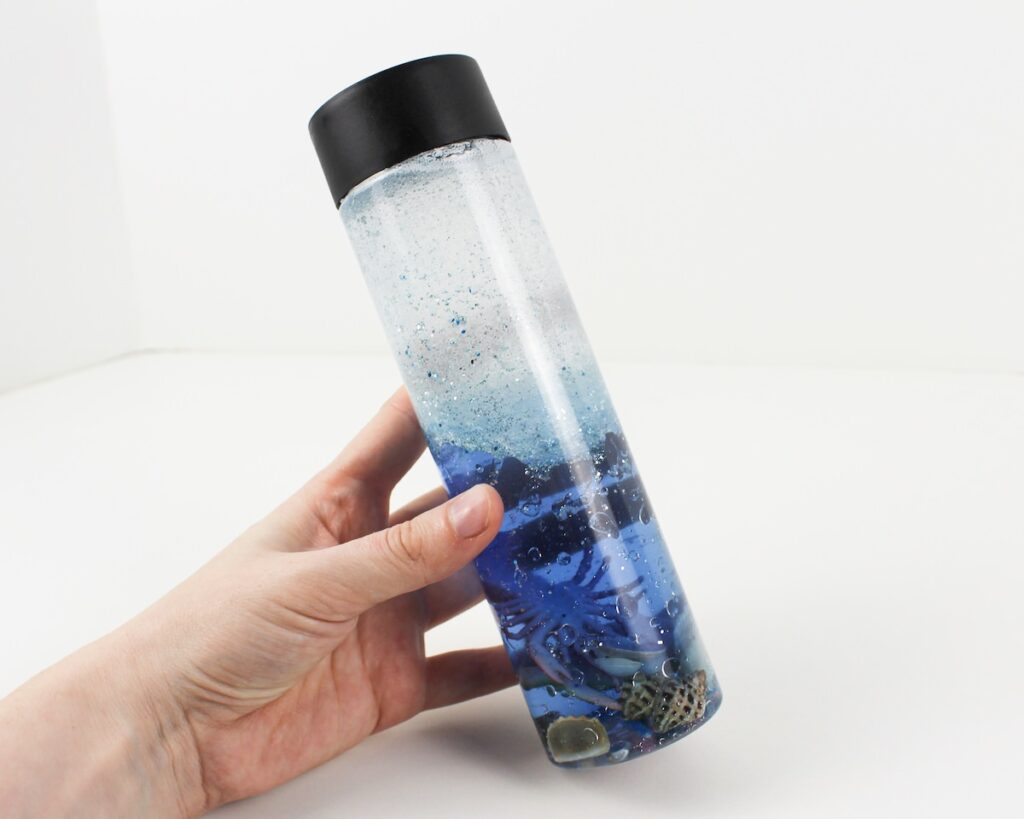 Hand holding a bubbly blue sensory bottle.