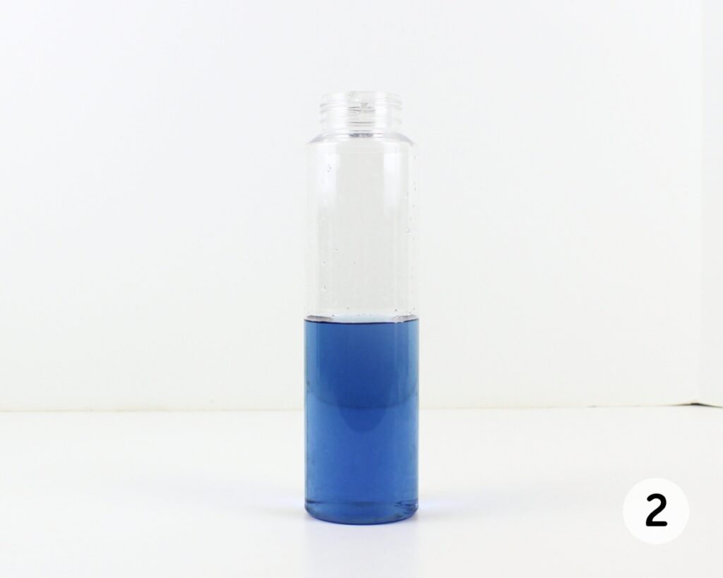 Tall plastic bottle filled halfway with blue water.