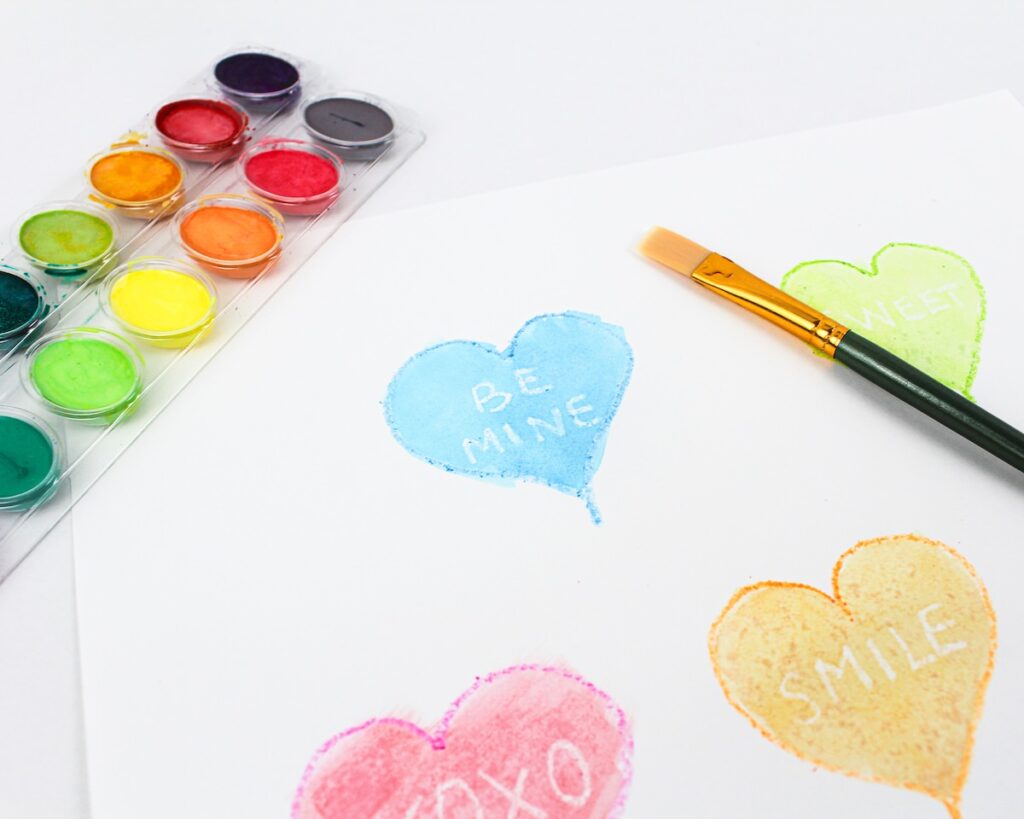 Painted blue heart craft with the words "be mine" appearing in white under the paint.
