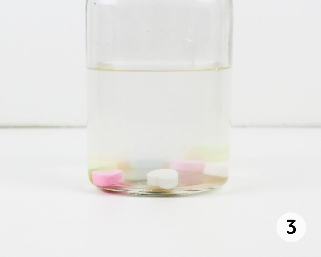 Conversation heart candies at the bottom of a jar of water.