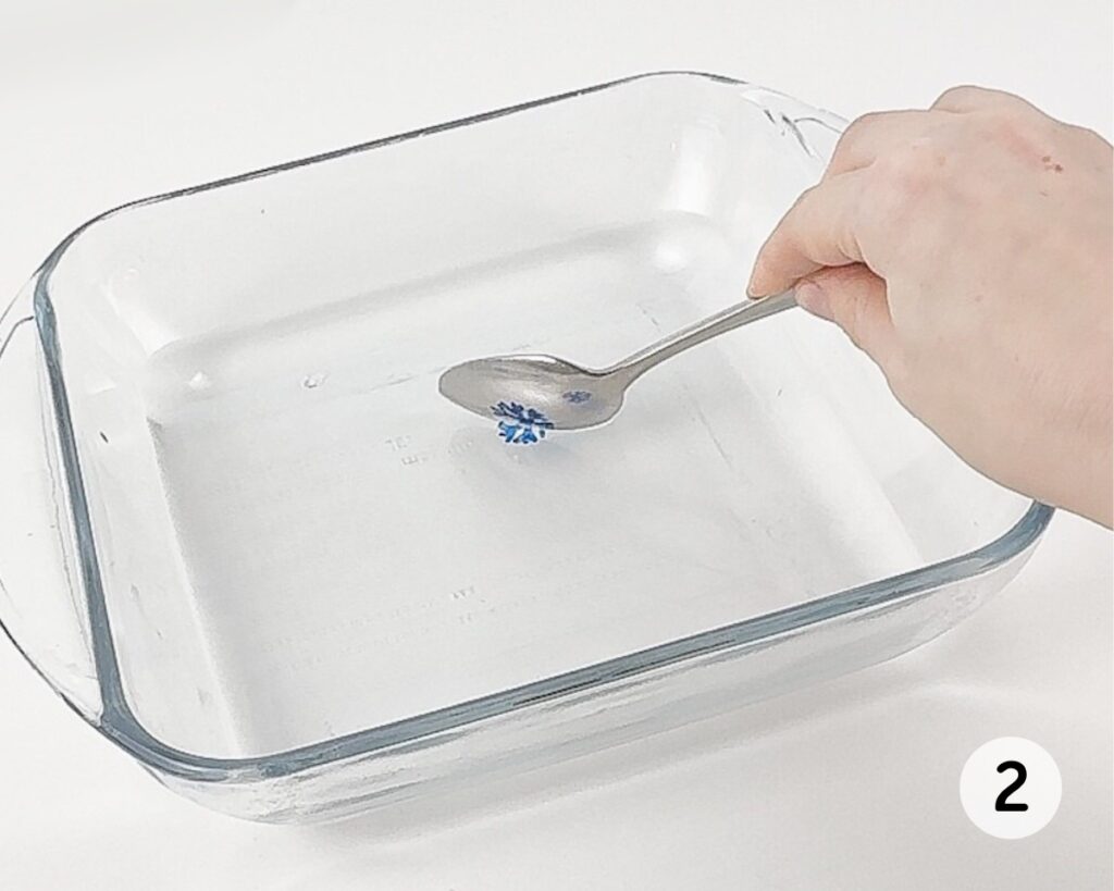 Blue snowflake drawing peeling off a spoon and into a dish of water.