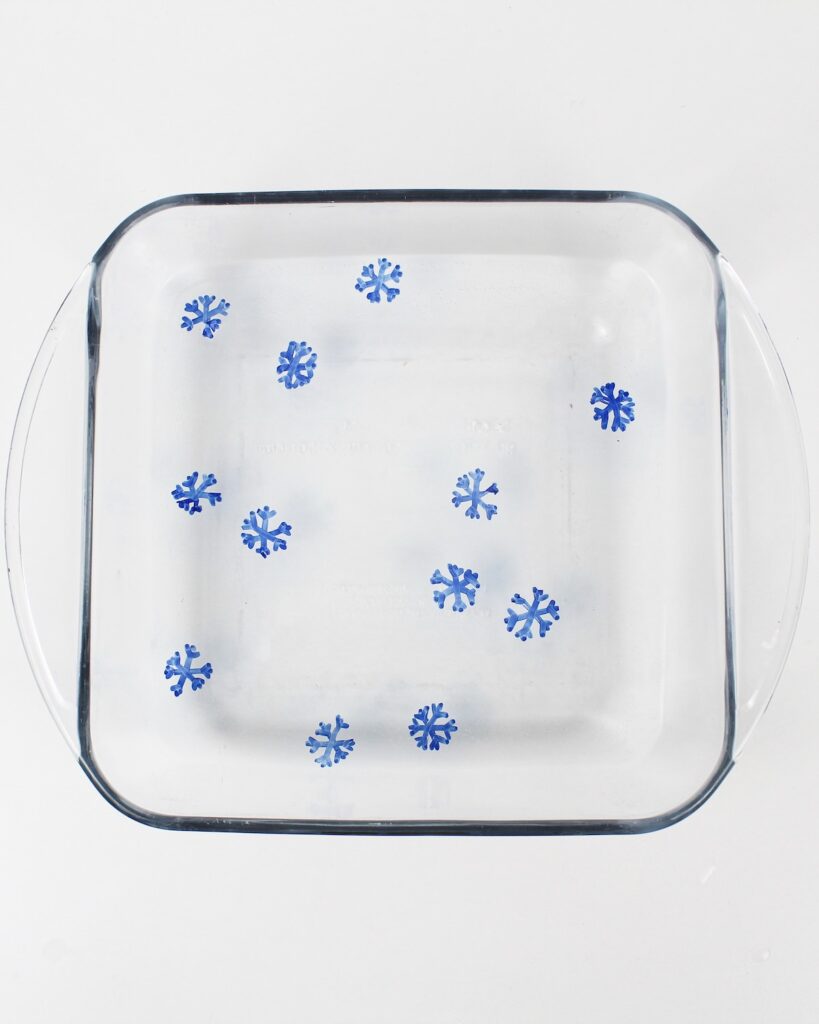 Floating blue snowflake drawings inside a glass dish with water.