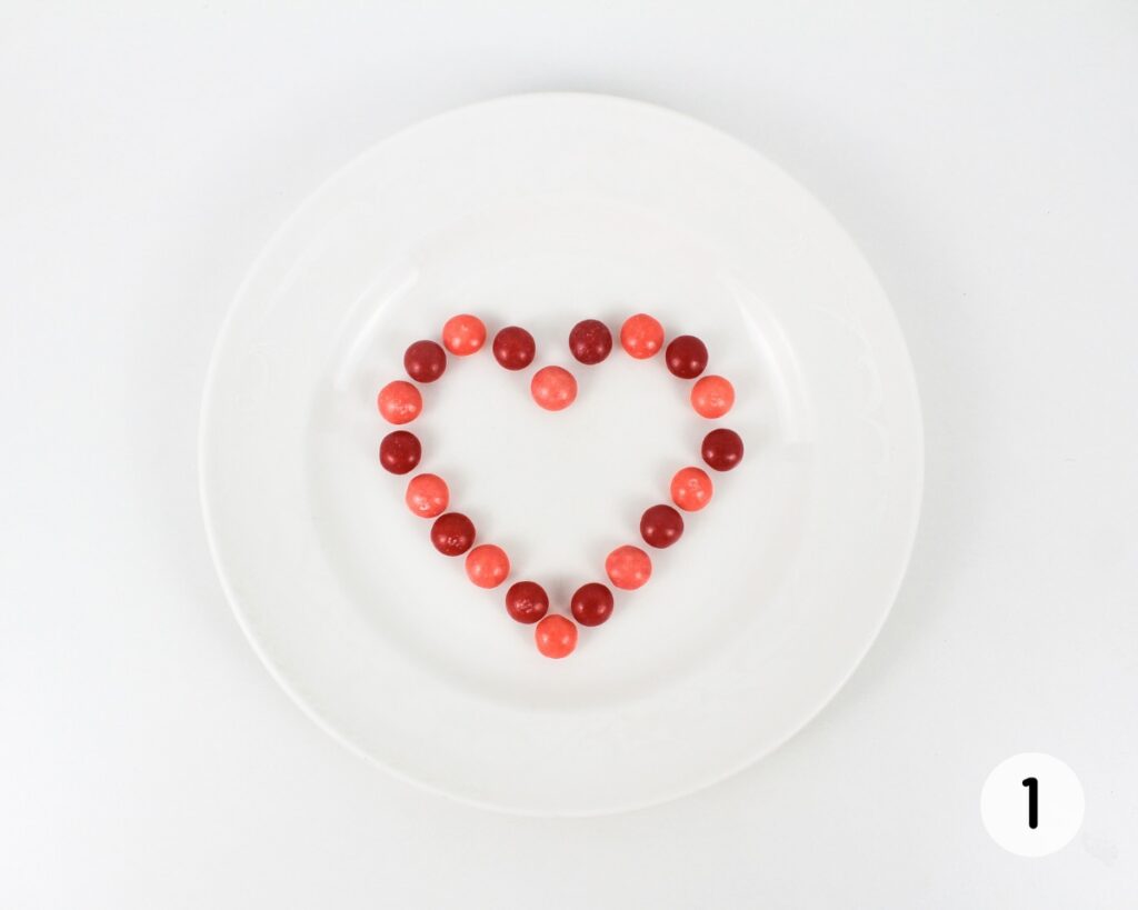 Skittles, arranged in the shape of a heart on a small plate.