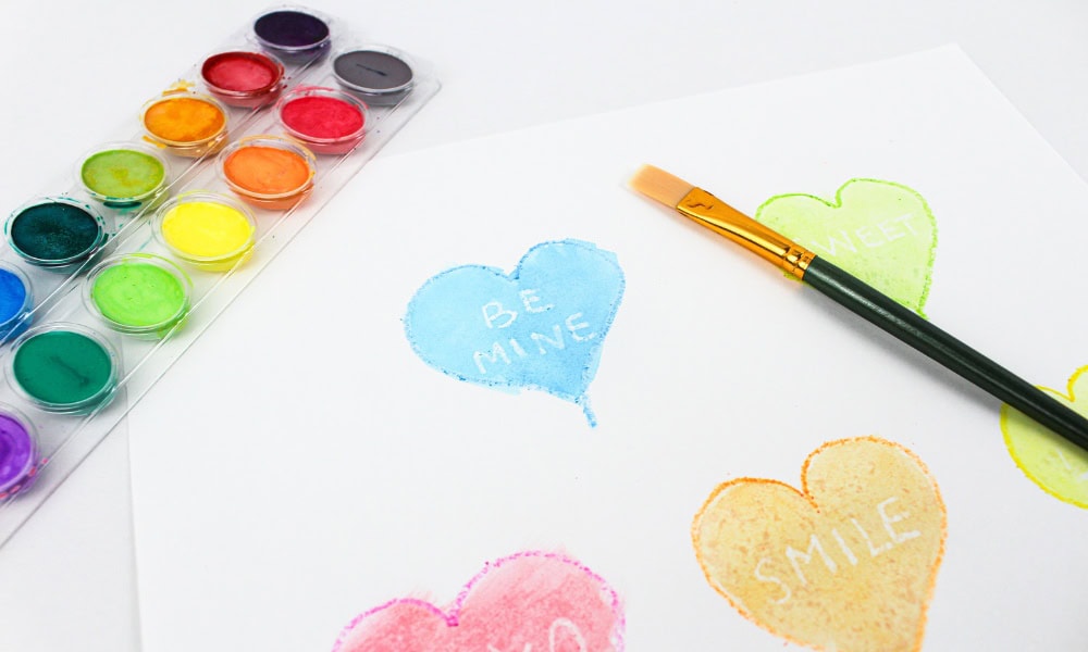 Painted blue heart craft with the words "be mine" appearing in white under the paint.