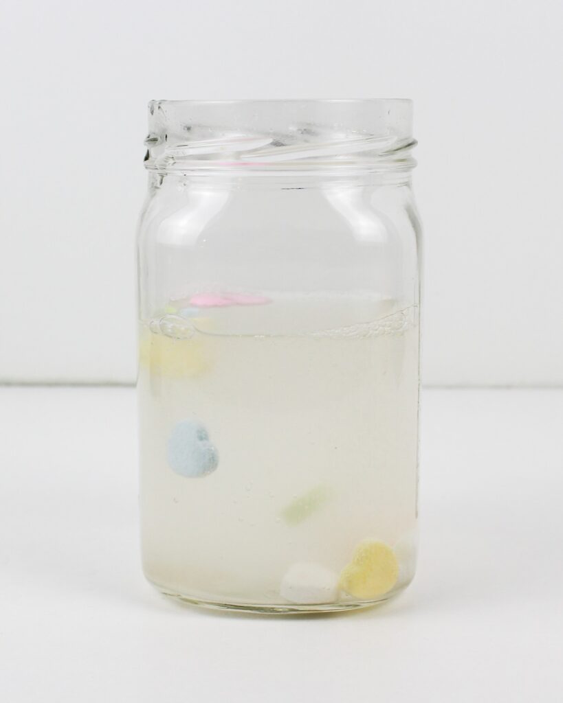 Heart candies floating up in a jar of water.