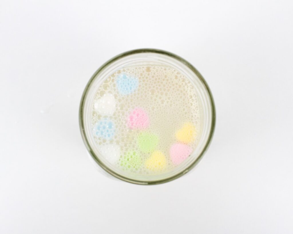 Conversation heart candies floating at the top of a jar of water.