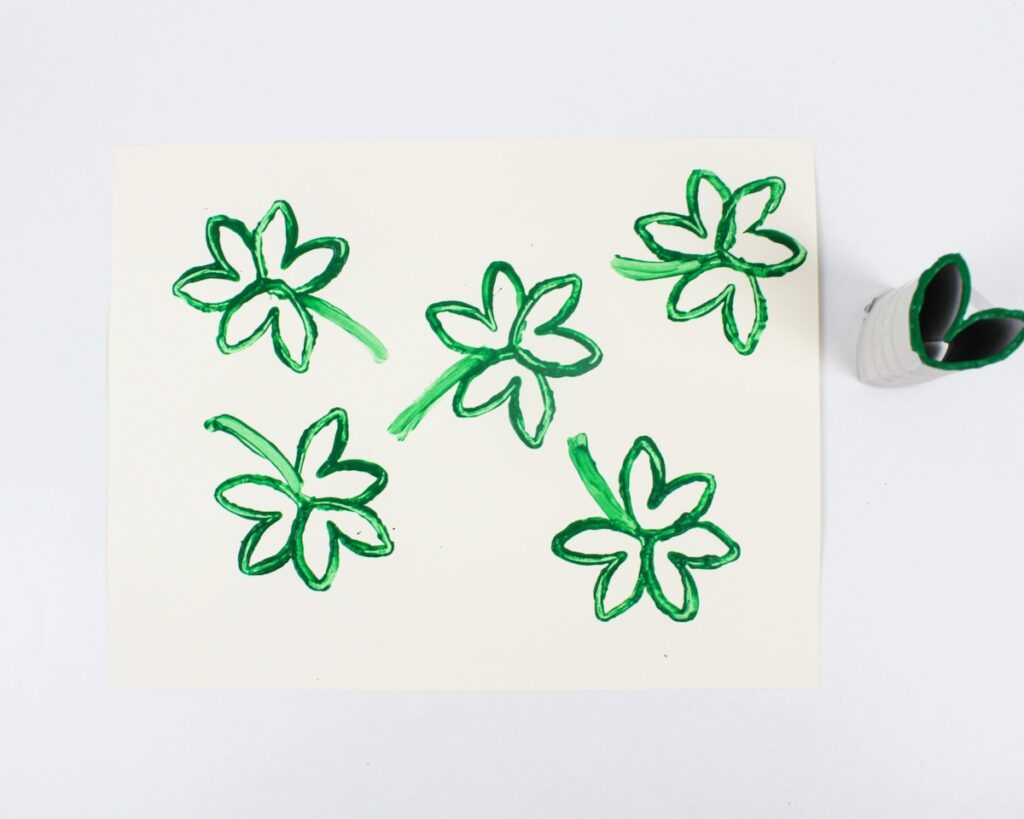 Stamped shamrock craft next to paper roll stamp.