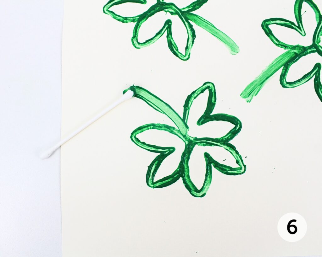 Q-tip painting a stem on the stamped shamrocks.