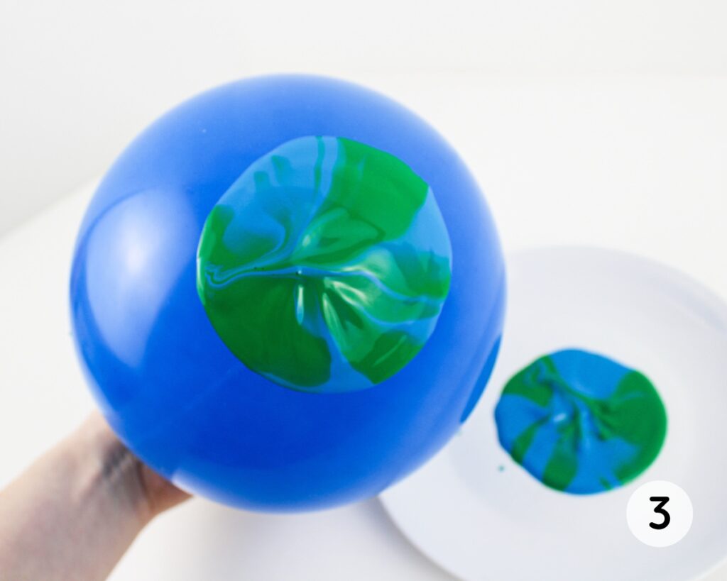 Inflated balloon dipped in blue and green paint.