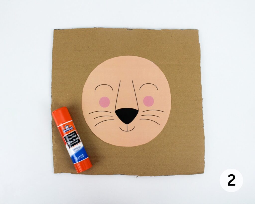 Lion face template glued to a square piece of cardboard.