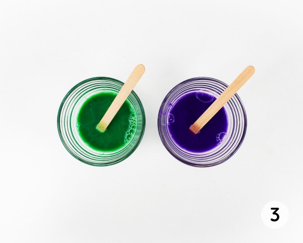 2 small bowls containing purple and green paint.