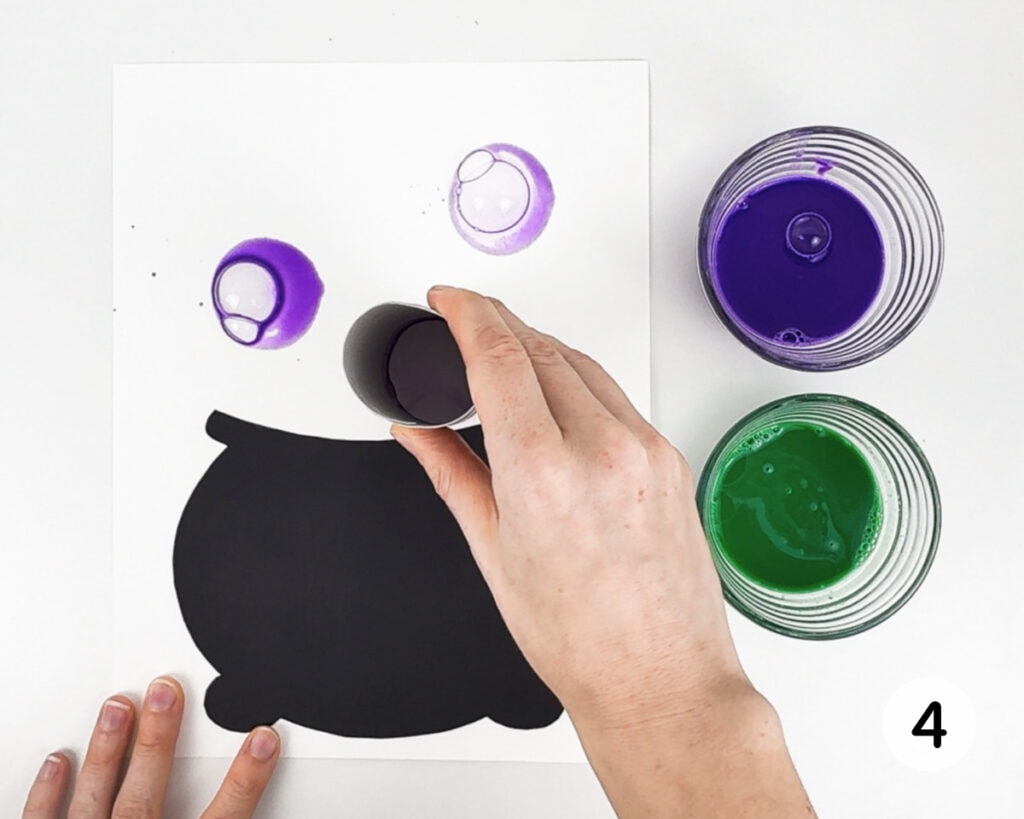 Hand stamping bubbles above the cauldron shape using a toilet paper roll.